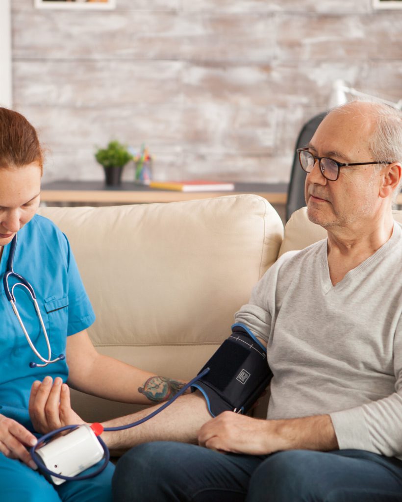 Female doctor in nursing home checking old man blood pressure.